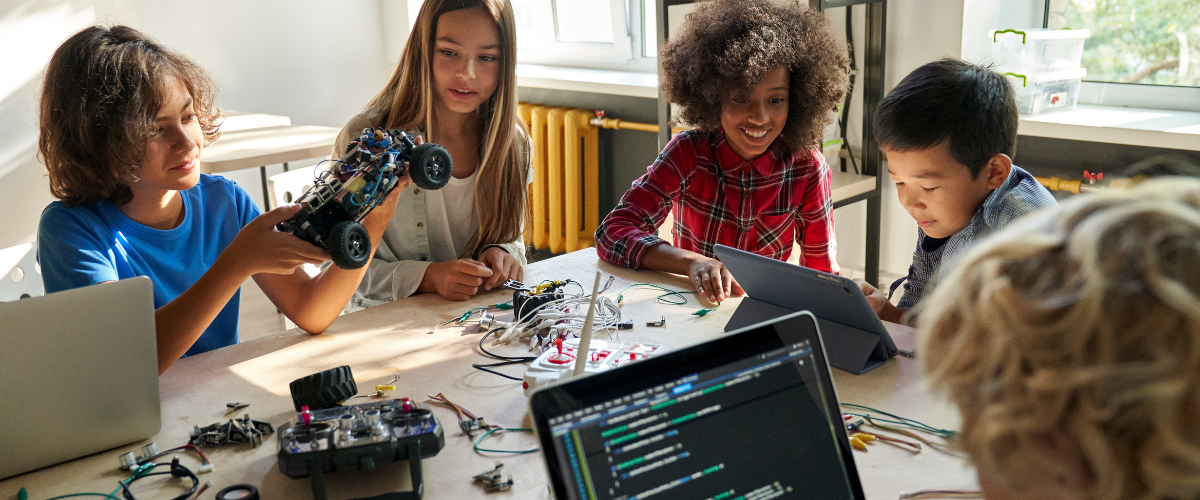 Kids sitting around a table coding and building