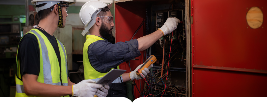 Two workers in safety gear testing electrical components