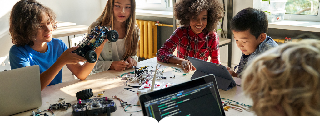 Kids sitting around a table building a robotic car