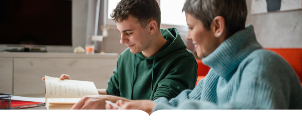 Teenager reading a book with an adult